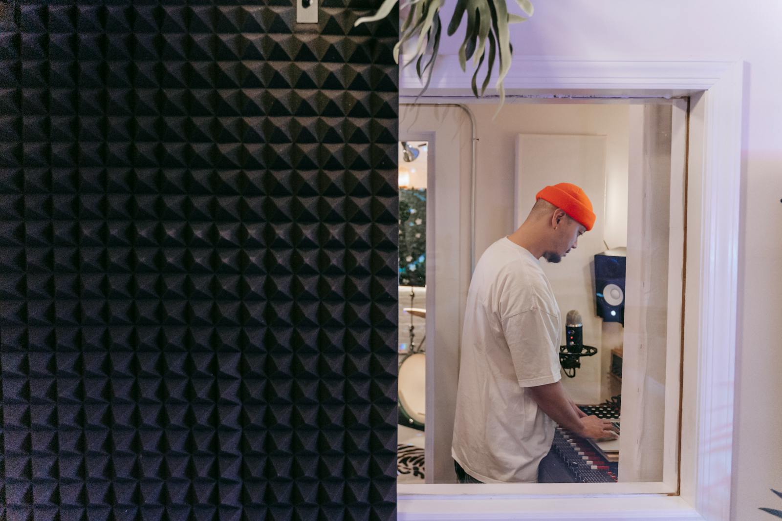 Man in White Shirt Wearing Orange Beanie Inside a Music Studio